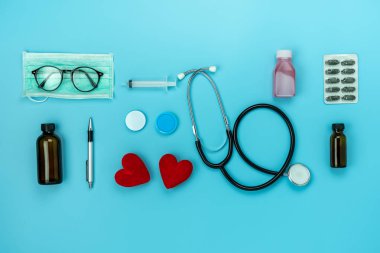 Masa üstü görünüm aksesuar sağlık ve tıbbi arka plan kavramının havadan görüntü. Kırmızı kalp ve stetoskop mavi kağıt üzerinde temel nesneleri ile. Hastanede doktor tedavi hasta için fikir Düz yatıyordu.