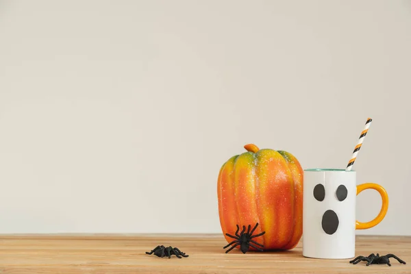 Accessories of decorations Happy Halloween day background concept.Cup of drink with pumpkin object to party season with spider on modern rustic brown & white backdrop at home office desk studio.