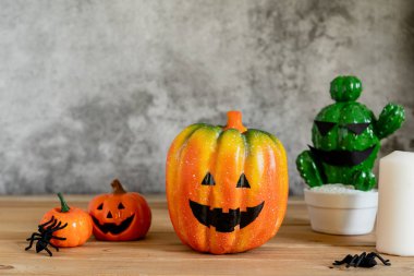 Dekorasyon aksesuarları Mutlu Cadılar Bayramı arka plan kavramı. Ürkütücü balkabaklarıyla Jack O Lantern kaktüsü modern rustik kahverengi ve beyaz taş fon üzerinde örümceklerle parti sezonuna karşı çıkıyor..