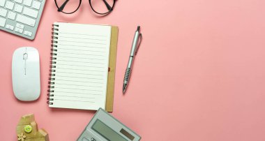 Ev arkası kavramından çalışmak için aksesuar ofis masasının en üstteki görünümü. Boş alan dizüstü & klavye ve modern kırsal pembe kağıt üzerinde gözlüklü hesap makinesi düzlüğü.