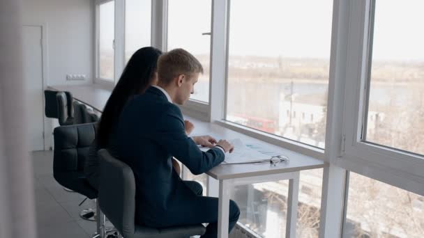 Mladí podnikatelé, pracující na projektu obchodní sedí u okna v moderní kanceláři.