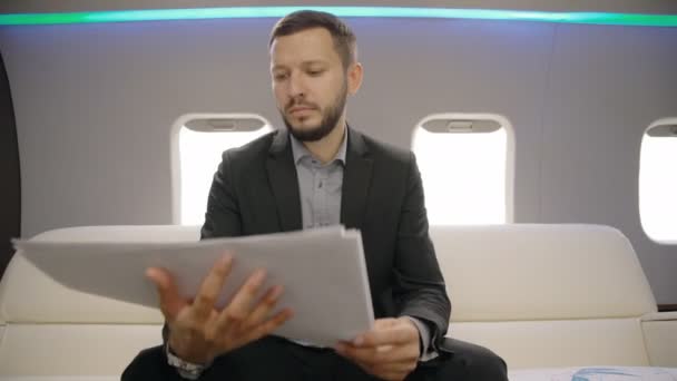 Porträt eines männlichen Investors, der während des Fluges mit seinem Privatflugzeug die Marktsituation auf Papier analysiert. Aero-Anwalt