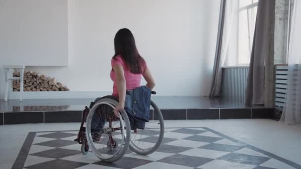 erwachsene Frau im Rollstuhl verbringt Zeit zu Hause und schaut auf c