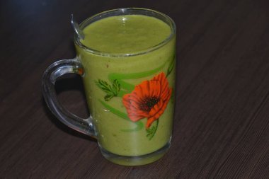 Siyah bir tezgahın üzerinde berrak bir bardakta tropikal meyvelerden oluşan kalın bir kokteyl.