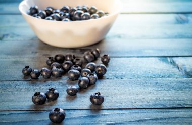 Olgun yaban mersini kase ve mavi ahşap masa