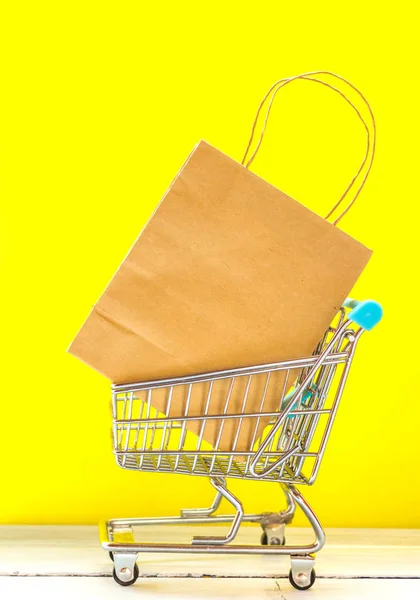 黄色の背景にショッピング コンセプト ミニチュア ショッピングカート ショッピング バッグ小売店します — ストック写真