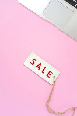Pembe arka planda satış etiketi ve dizüstü, online alışveriş