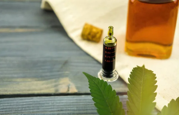 Syringe bottle of full spectrum Cannabis oil on wooden table