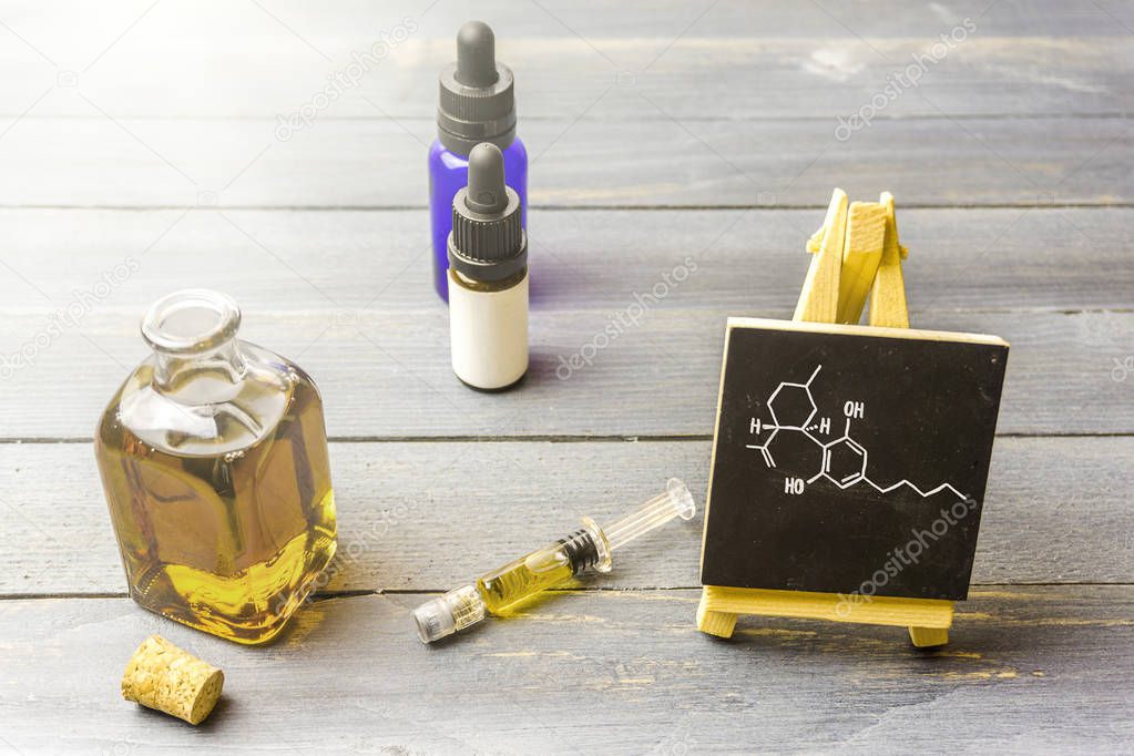 Cbd oil in glass bottle and chalkboard with molecule drawing on 