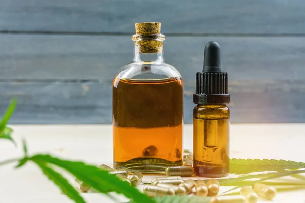 Clear CBD Cannabidiol capsules and cannabis oil on wooden table — Stock Photo, Image