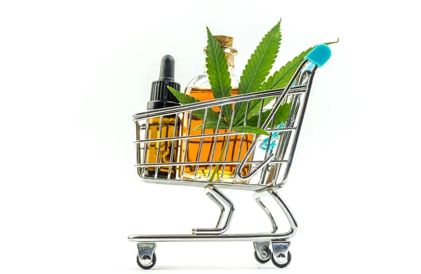 マリファナの葉と医療大麻油cbdとスーパーマーケットのトロリー, 白で隔離 — ストック写真