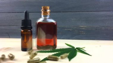 Cbd Kenevir yağı ve Cbd kapsülleri ile Cam Şişeler masada yavaş hareket halinde dökülme