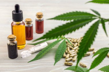 Full spectrum Cannabidiol CBD oils, capsules and crystals isolate on wooden backdrop clipart