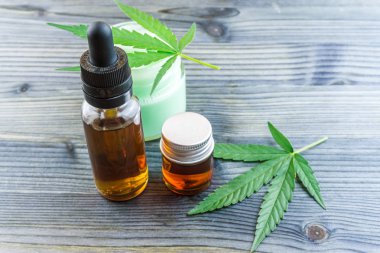 Cam şişe esrar Cbd yağlar ve masada kenevir yaprakları ile Cbd losyon jel küçük kavanoz