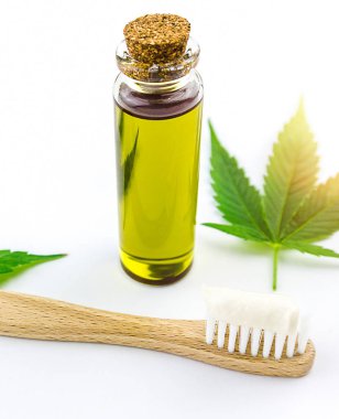 Cannabis CBD oil and toothpaste with Cannabis leafs and wooden toothbrush clipart