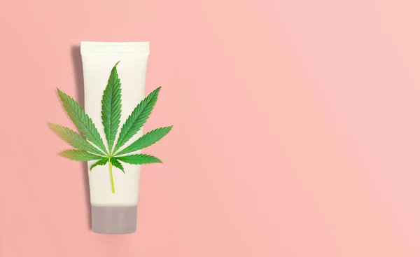 CBD Cannabis Hemp topical cream balm with cannabis leaf on pink backdrop