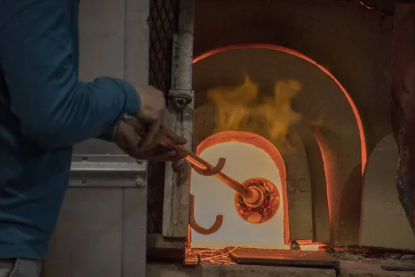 A glass blowing artist forms a blob of glass into a vessel using a gas torch  in Vermont Stock Photo - Alamy