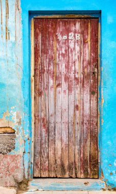 Trinidaad, Küba 26 Kasım 2017 - soluk kırmızı kapı kırık sıva ile mavi tuğla duvar