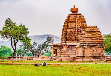 Badami, Hindistan, 18 Mar 2018: İki kadın karmaşık Hintçe tanrılarla oyulmuş bir Bhuthnath Tapınağı önünde çim bakımı