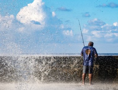 Havana, Küba, 20 Kasım 2017 - Erkekler sörf yapmaya devam ettikçe dalgalar Malecon duvarını aşıyor