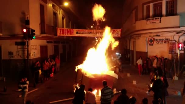 Cuenca, Ecuador - December 31, 2018 - Bonfire is fed on street at midnight on New Year Eve — стоковое видео