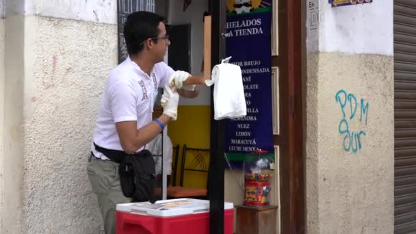 Cuenca, Ecuador - December 31, 2018 - Ο άντρας φτιάχνει καραμέλες αλατιού και πουλάει σε γυναίκα πελάτη — Αρχείο Βίντεο