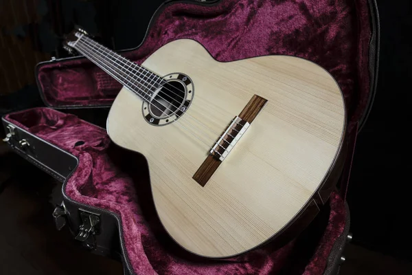 Guitarra acústica senta-se em caixa forrada de veludo vermelho — Fotografia de Stock