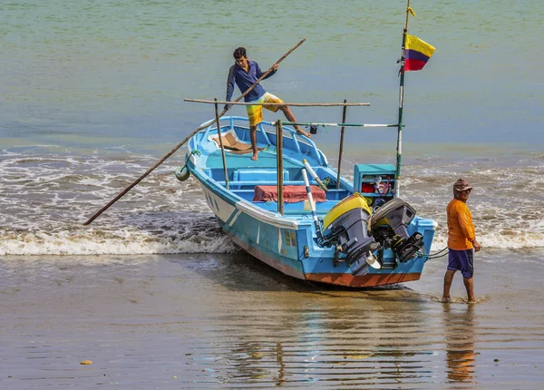 Puerto lopez, ecuador - 12. september 2018 - männer versuchen, boot im sand zu halten, während sie auf hilfe warten, um es am ende eines tages den strand hochzuziehen. — Stockfoto