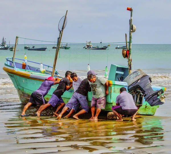 Puerto López, Ecuador - 12 de septiembre de 2018 - Seis hombres trabajan juntos para llevar el barco pesquero a la playa al final de un día . — Foto de Stock