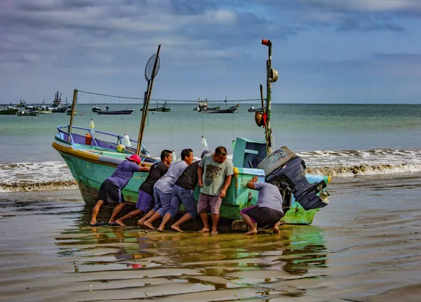 Puerto lopez, ecuador - 12. september 2018 - sechs männer arbeiten zusammen, um am ende eines tages ein fischerboot an den strand zu bringen. — Stockfoto