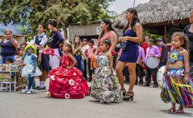 San Pedro, Ecuador - September 15, 2018 - Children compete in a costume contest, with their mothers standing behind them.