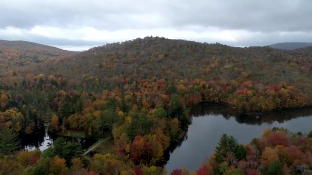Letecká Drone - Fly přes jezero a kopce plné stromů barevný podzim ve Vermontu. — Stock video