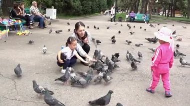 Almatı, Kazakistan - 20170531 - Anne kızı nasıl Park güvercin beslemek için öğretir..
