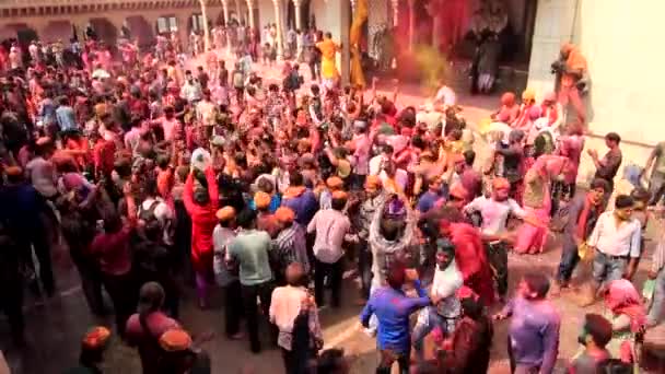 群衆がダンス中に空気中の腕をスローするようにバーサーナ、インド - 20180223 - ホーリー祭 - 上から見た - 塗料がスローされます。. — ストック動画