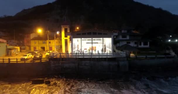 La Entrada, Ecuador - 20180914 - Drone antenne - Drone benaderingen langzaam glas Fronted kerk met mensen binnen nachts bij hoog tij. — Stockvideo