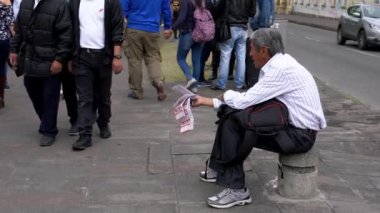 Cuenca, Ekvador - 20181003 - Cuenca bağımsızlık günü festivali - piyango bilet satıcısına otururken bir satış yapar.