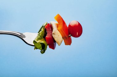 Mavi arka planda çatallı bir salata