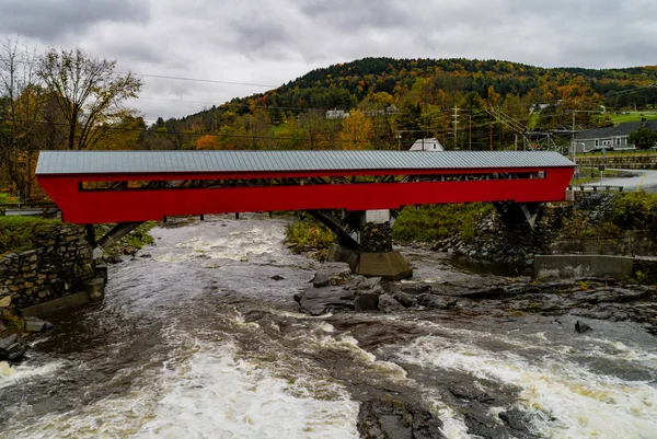 まず 1883 年に建てられた赤い屋根付きの橋にまたがる急速に流れる川 — ストック写真