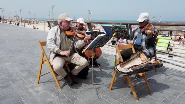 Tel Aviv, Israël-2019-04-27-oudere snaar muzikanten op het strand met geluid 3-kijkend naar het strand — Stockvideo