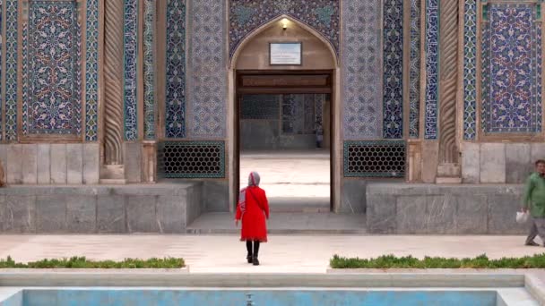 Керман, Иран - 2019-04-06 - Женщина в красном входит в мечеть Ганджали — стоковое видео