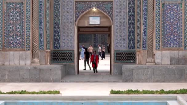 Керман, Иран - 2019-04-06 - Женщина в красном выходит из мечети Ганджали, пока дети играют на заднем плане — стоковое видео