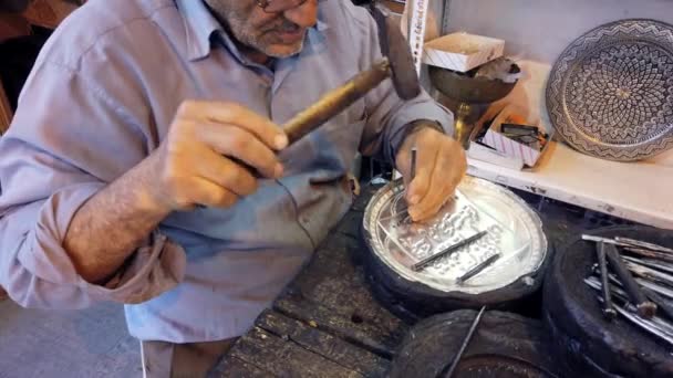 Isfahan, Iran-2019-04-12-oudere man gebruikt hamer en beitel om zilver Bowl-Close te graveren — Stockvideo