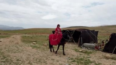 Şiraz, İran - 2019-04-09 - Kırmızı Elbiseli Qashqai Kadın At Geçmiş Çadırlara Biniyor
