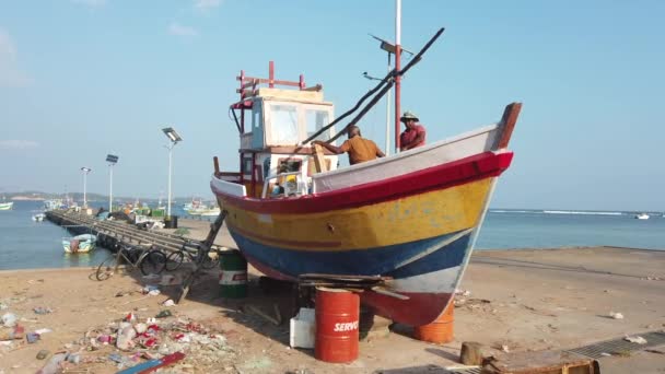 加勒, 斯里兰卡 - 2019-04-01 - 两名男子在海滩上的干船坞小船上工作 - 茎前 — 图库视频影像