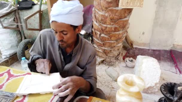 Luxor, Égypte - 2019-05-01 - L'homme sculpte un motif sur une tablette d'argile pour la décoration — Video