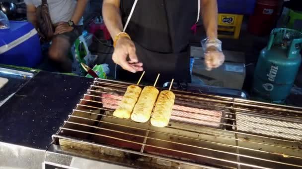Phayao, Ταϊλάνδη-2019-03-08-προμηθευτής τροφίμων περιστρέφεται πιπέρι κοτόπουλο λουκάνικο — Αρχείο Βίντεο