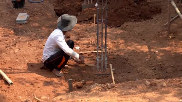 Chiang Saen, Thailand - 2019-03-10 - Man Scoops Dirt from Base of Ribar Tower — стоковое видео