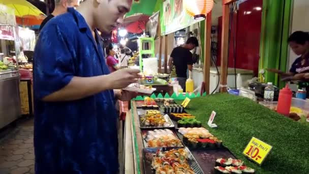 Chiang Mai, Thailand-2019-03-15-man väljer bitar av sushi på Market stall — Stockvideo