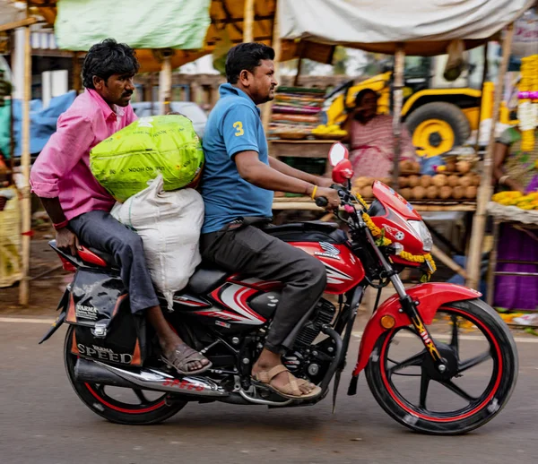 Двое мужчин едут на мотоцикле с большими сумками для рынка, с размытым фоном движения — стоковое фото