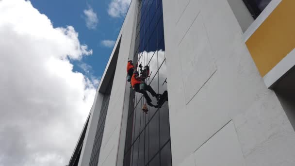 Cuenca, Ecuador - 2019-02-09 - Window Washers Clean Glass Wall of Highrise Against Fluffy Clouds — стокове відео